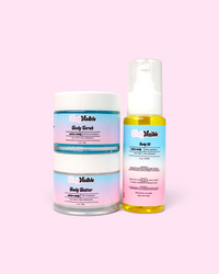 Three Visible skincare products arranged on a solid pink background: two white-lidded jars of body scrub and body butter with pastel gradient labels, and one clear pump bottle of body oil containing yellow liquid.